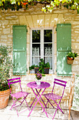 Sitzplatz mit violetten Gartenmöbeln vor französischem Steinhaus