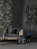 Back velvet sofa and stool in front of black wall