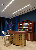 Curved gilt bar and drinks cabinet against blue wall