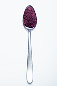 Acai berry powder on a spoon against a white background