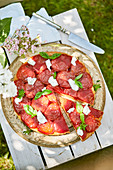 Summery tomato tart outdoors on a wooden box