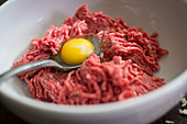 Ingredients for meatball: minced meat and egg yolk in a bowl
