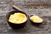 Ghee in a bowl and on a wooden spoon