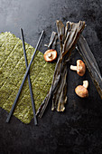 Frische und getrocknete Algenblätter daneben Shiitakepilze