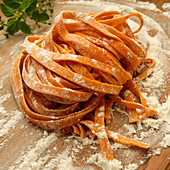 Roasted red pepper pasta on dough board with flour