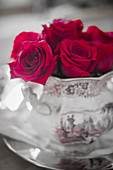 Red roses in china pot with pink and grey landscape pattern