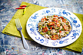 Wholewheat homemade orecchiette pasta with broccoli florets, cherry tomatoes, red chilli in a plate with blue decorations