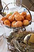 Brown coloured eggs in a silver dish behind a painted Easter egg in a straw nest
