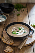 Mushroom soup with soured cream and parsley garnish, bread on a side