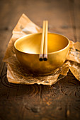 A golden bowl with chopsticks