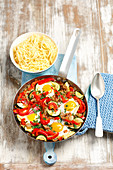 Minced meat with peppers, courgette and fried eggs served with pasta