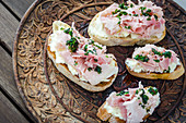 Bruschetta toasted sliced baguette, ciabatta and sourdough bread with spreadable soft cheese and ham drizzled with herbs