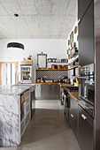 Schwarze Einbauküche mit Marmor-Kücheninsel unter Betondecke
