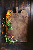 Olivenblätter, Orangenschale und getrocknete Aprikosen auf Holzschneidebrett