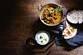 Asiatisches Ziegenfleischcurry serviert mit Reis, Fladenbrot und Dip