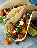 Soft taco shells with sweet potatoes, beans and rocket