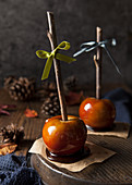 Two toffee apples with almond flakes and natural wooden sticks
