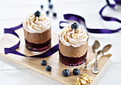 Nut and nougat mousse in glasses with blueberries and whipped cream, served on a wooden board (vegan)