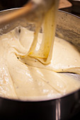 A cook preparing cheese sauce for making macaroni cheese