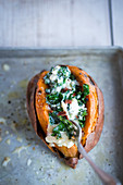 A sweet potato filled with kale, bacon and cheese