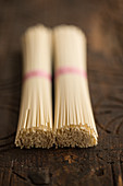Two bundles of udon noodles on a wooden background