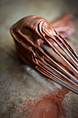 A whisk covered with chocolate cream