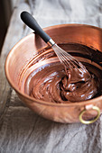 Chocolate cream with a whisk in a copper mixing bowl