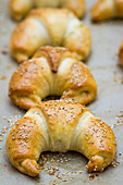 Croissants with sesame seeds on a baking sheet