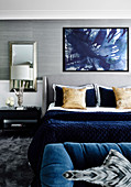 Doppelbett im Schlafzimmer mit blauen Accessoires und Tapete mit Metallgewebe