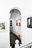 View from the stairwell through arched opening in the hallway with bench