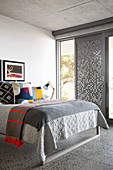 Verschiedene Farben und Muster auf dem Bett im grauen Schlafzimmer