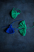 Hand-made green and blue tassels on black surface