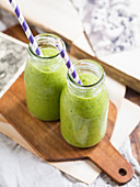 Green vegan smoothie in two small bottles