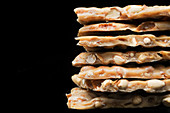 Stack of peanut brittle on a black background (close-up)