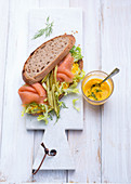 A salmon sandwich with gherkins and carrot cream