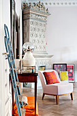 Pale pink easy chair in front of antique tiled stove in corner