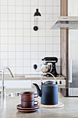 Black teapot and stacked teacups on island counter