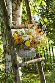 Rural late summer arrangement in basket hung on ladder