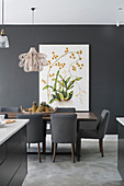 Dining table with grey upholstered chairs, picture with botanical motif on grey wall