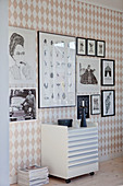 Plan chest on wheels below gallery of pictures on wall with diamond-patterned wallpaper