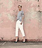 a young blonde woman wearing a stripped shirt, white trousers and snakeskin shoes