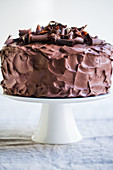 A three-layer chocolate cream cake on a cake stand