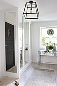 Silver console table below window and wardrobe with mirrored doors in bedroom