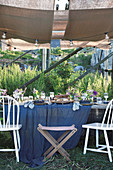 Fürs Sommerfest gedeckter Tisch unter Holzständern mit Stoffbahnen