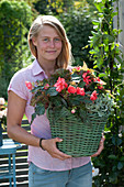 Frau trägt Korb mit Begonia Iconia 'Miss Malibu'