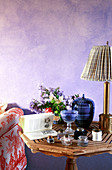 Jars, book and flowers on table in front of purple wall