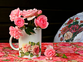 Pink roses in rose-patterned mug against black background