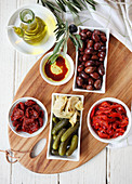 Verschiedene Antipasti (getrocknete Tomaten und Paprika, Kalamata-Oliven, Essiggurken, Artischocken, Olivenöl mit Balsamico)