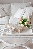 Cups, gift and vase of roses on tray on coffee table