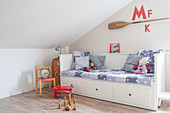 Bed with drawers below under sloping ceiling in child's bedroom